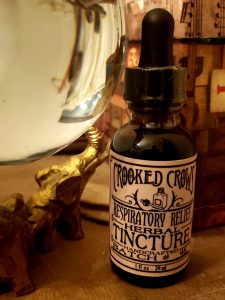 Crooked Crows herbal tincture in an amber dropper bottle on a dark table