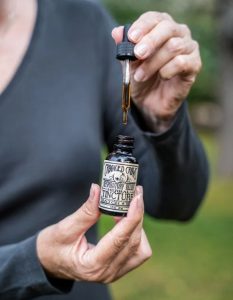 Hand holding a Crooked Crows dropper bottle